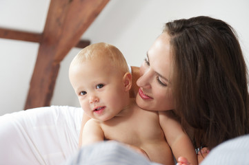 Baby and mother smiling on bed