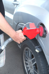 Hand holding a nozzle while fueling car