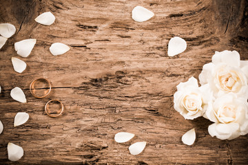 wedding rings and rose on a wooden background