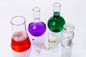 Laboratory glassware with liquids of different colors and tablet