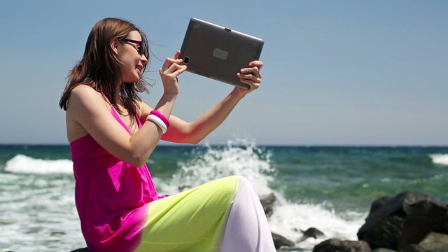 Beautiful woman chatting on tablet computer by the sea