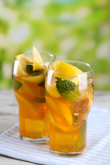 Iced tea with lemon and mint on wooden table, outdoors