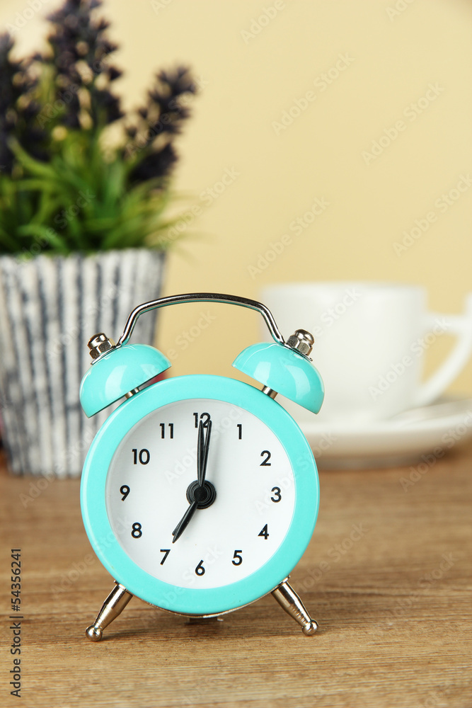 Wall mural Blue alarm clock on table on beige background