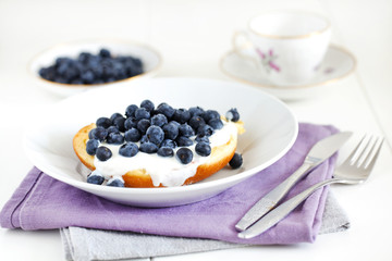 Brioche or english muffin with blueberries and cream