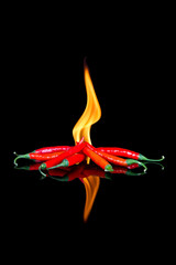 Red chilli on black surface with flames