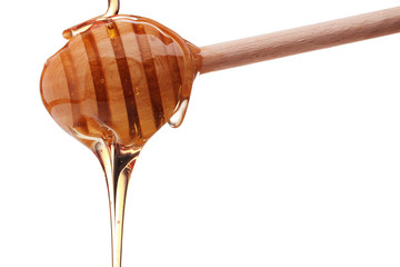 Honey dripping from a wooden honey dipper isolated on white back