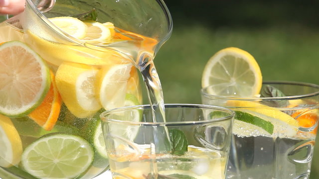 Close-up of jug with fresh lemonade pouring to glass.