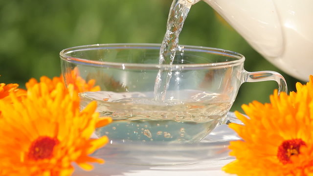Cup and pouring marigold (calendula) tea.