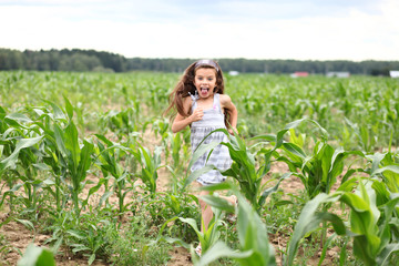 Fototapeta premium Joyful little girl running through the corn field