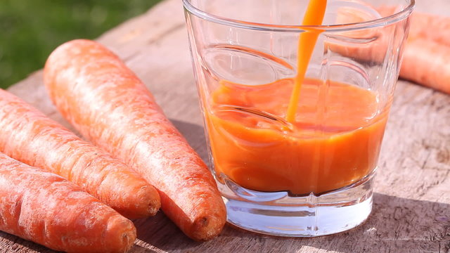 Close-up of glass with pouring carrot juice.