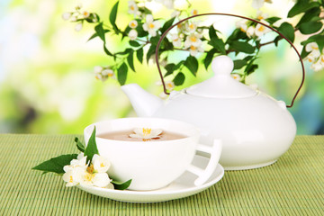 Cup of tea with jasmine, on bamboo mat, on bright background
