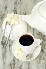 Cup of coffee, teapot and sugar-bowl on color wooden background