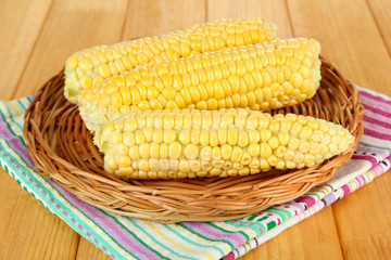 Fresh corn on wicker mat, on wooden background