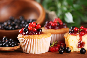 Tasty muffins with berries on wooden table