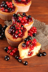 Tasty muffins with berries on wooden table