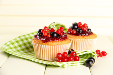 Tasty muffins with berries on white wooden table