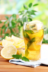 Iced tea with lemon and mint on wooden table, outdoors