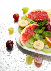 Assortment of sliced fruits on plate with drops