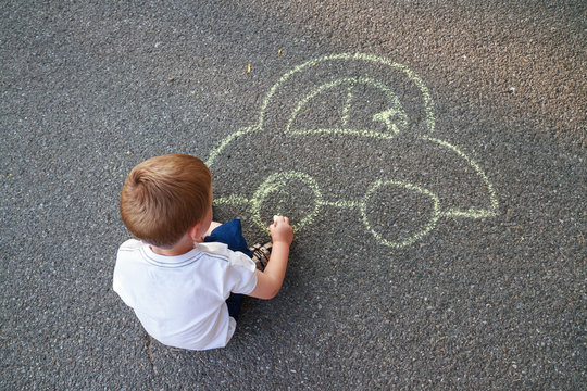 Boy drawing car with chalk
