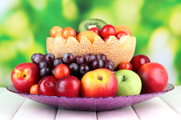 Assortment of juicy fruits on wooden table, on bright