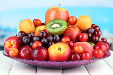 Assortment of juicy fruits on wooden table, on bright