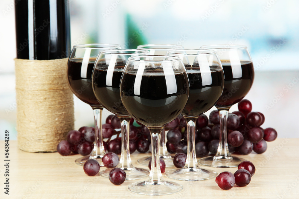 Wall mural Red wine in glass on room background