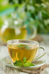Cup of herbal tea with fresh mint flowers on wooden table
