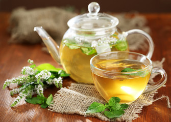 Cup and teapot of herbal tea with fresh mint flowers