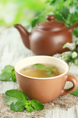 Teapot and cup of herbal tea with fresh mint flowers