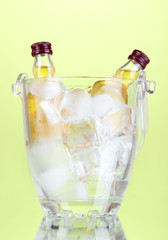 Minibar bottles in bucket with ice cubes,  on color background