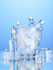 Minibar bottles in bucket with ice cubes,  on blue background