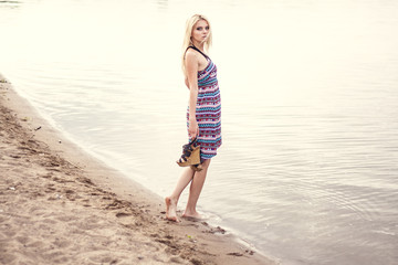 Young woman in dress walking alone on the beach