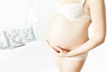 Fototapeta na wymiar Pregnant woman in white lingerie