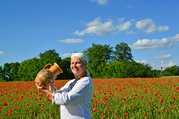 The rural woman drinks water from a jug in a poppy field