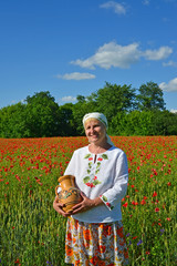 The rural woman costs with a jug in a poppy field