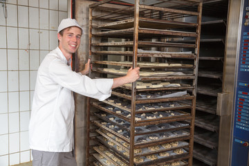 Baker pushing rack full of bread into the oven