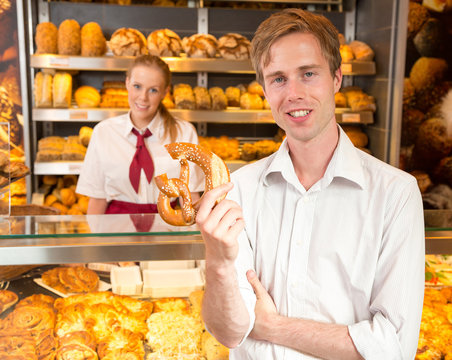 Customer holding a pretzel in baker's shop