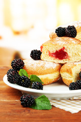 Tasty donuts with berries on wooden table