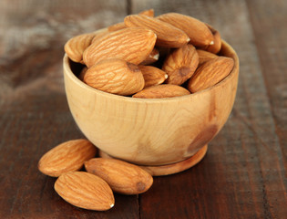 Almond in wooden bowl, on wooden background