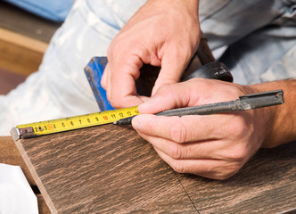 Man measuring a tile piece with a marker