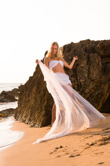 Woman wrapped in wedding veil on the beach