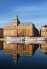 Old steam boats and buildings reflecting in water in Stockholm.