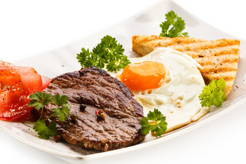 Grilled steak, toast, fried egg and vegetables
