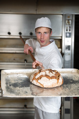 Bäcker mit einem Brot auf einem Brotschieber