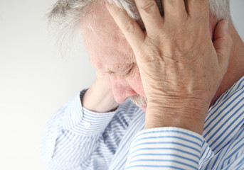 stressed older man holds his head in both hands