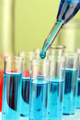 Laboratory pipette with drop of color liquid over glass test