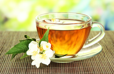 Cup of tea with jasmine, on bamboo mat, on bright background