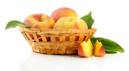 Ripe sweet peaches with leaves in basket, isolated on white