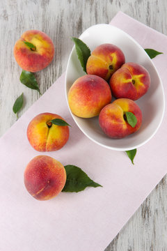 Peaches in plate on napkin on wooden table