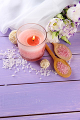 Beautiful pink candle with flowers on purple wooden background